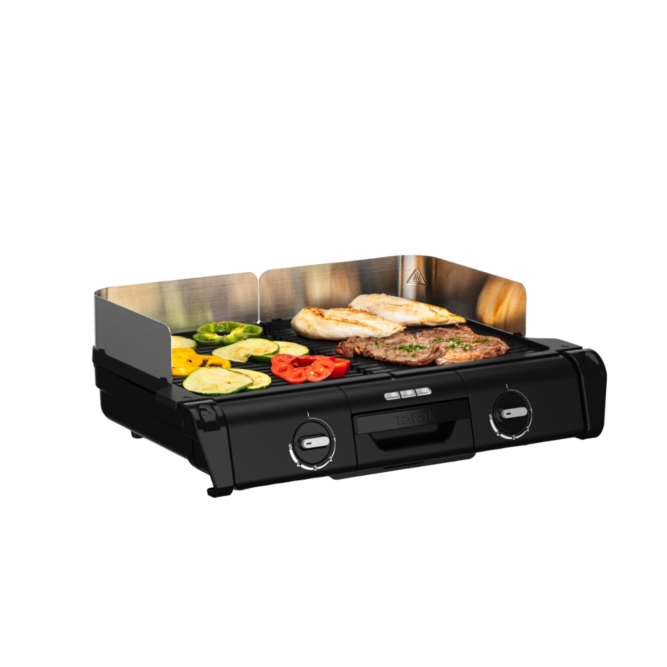 Ein schwarzer Kontaktgrill mit Hähnchenbrust, Steak und Gemüse.