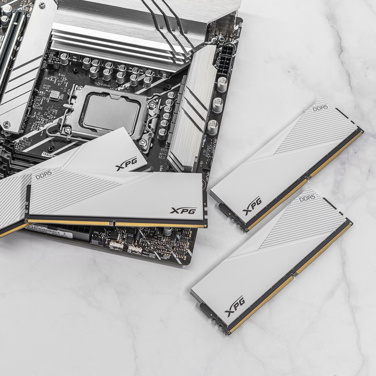 Mermer yüzeyde XPG logolu üç beyaz DDR5 RAM modülüne sahip bir anakart.