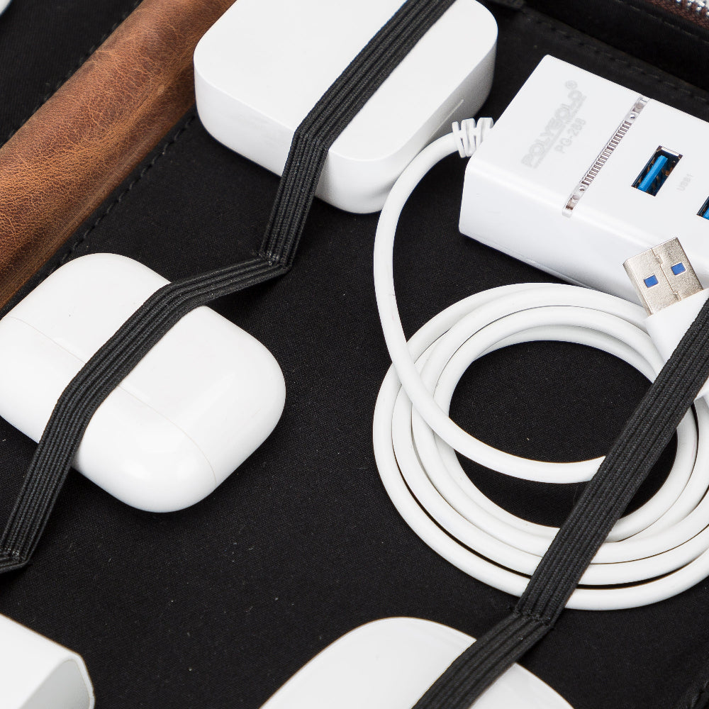 Beyaz kulaklık kılıfı, USB hub ve siyah kumaş üzerinde sarılı kablo.