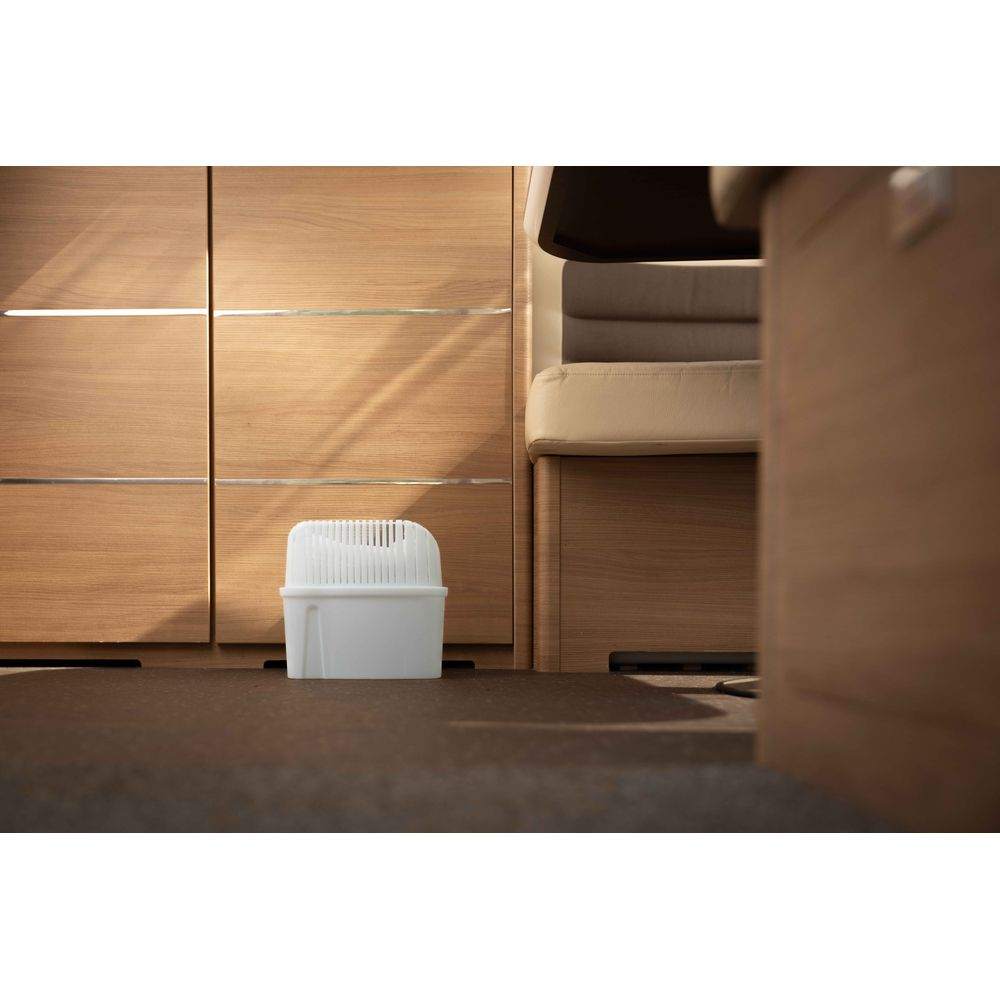 Un deumidificatore bianco su pavimento scuro davanti a mobili in legno.
