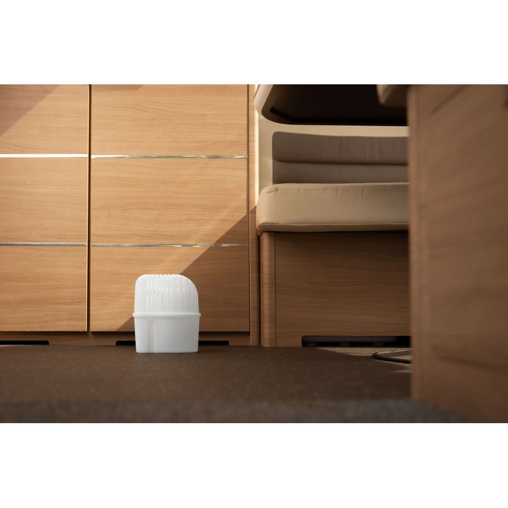 Un contenitore bianco si trova su un pavimento scuro davanti ad armadi in legno e un letto.
