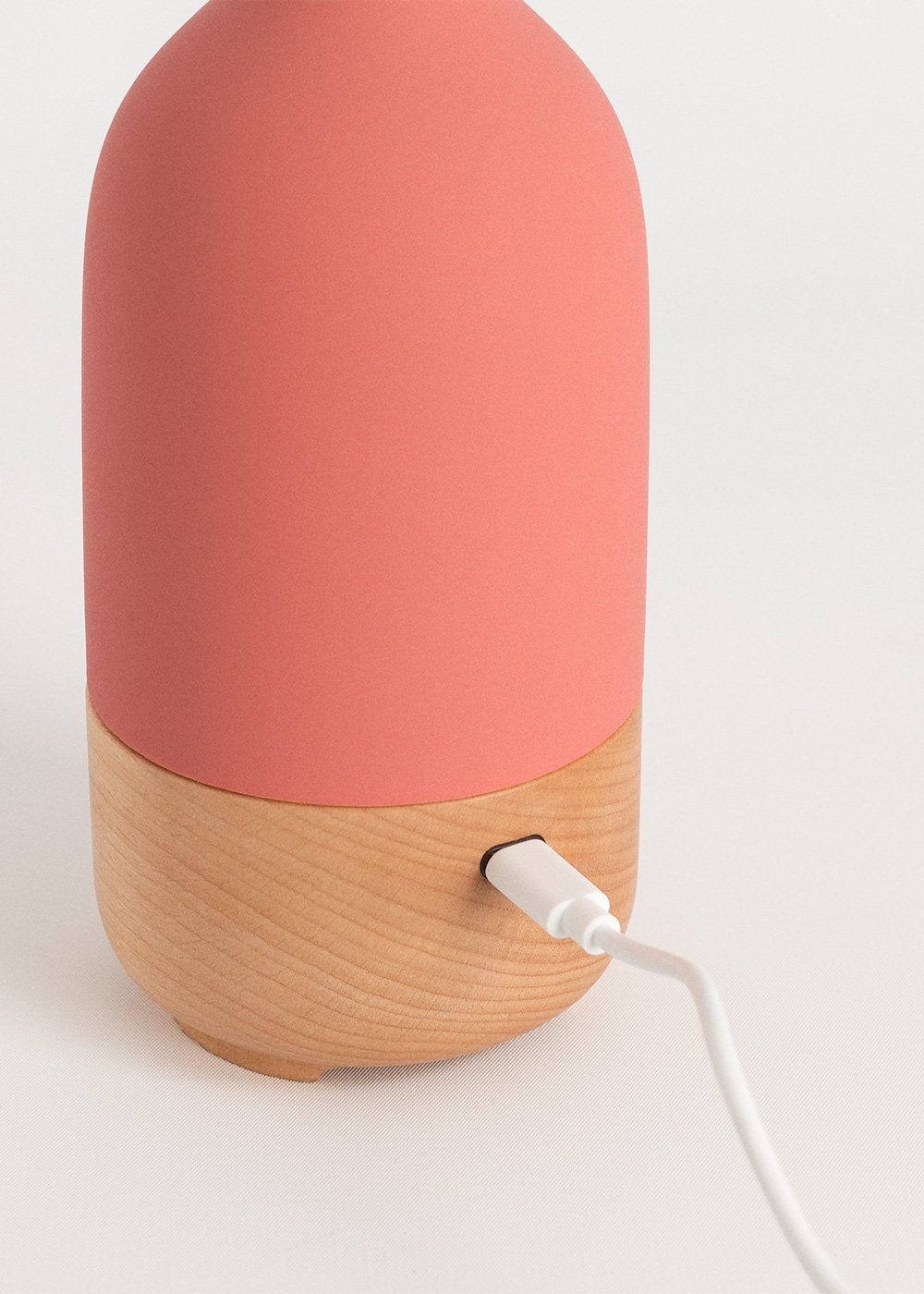 Una semiesfera coral con base de madera y puerto USB-C.
