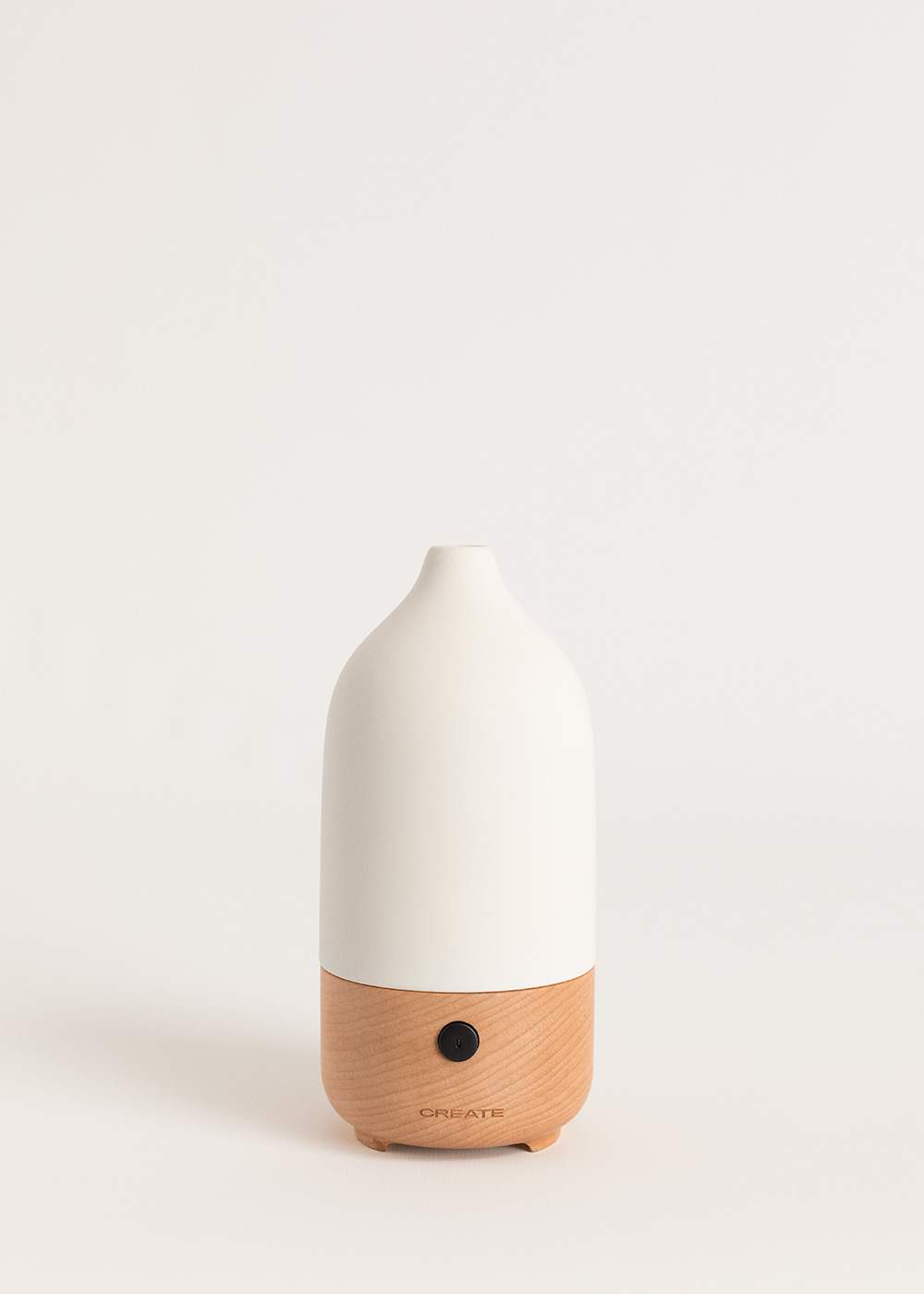 Un difusor blanco con base de madera y botón negro.