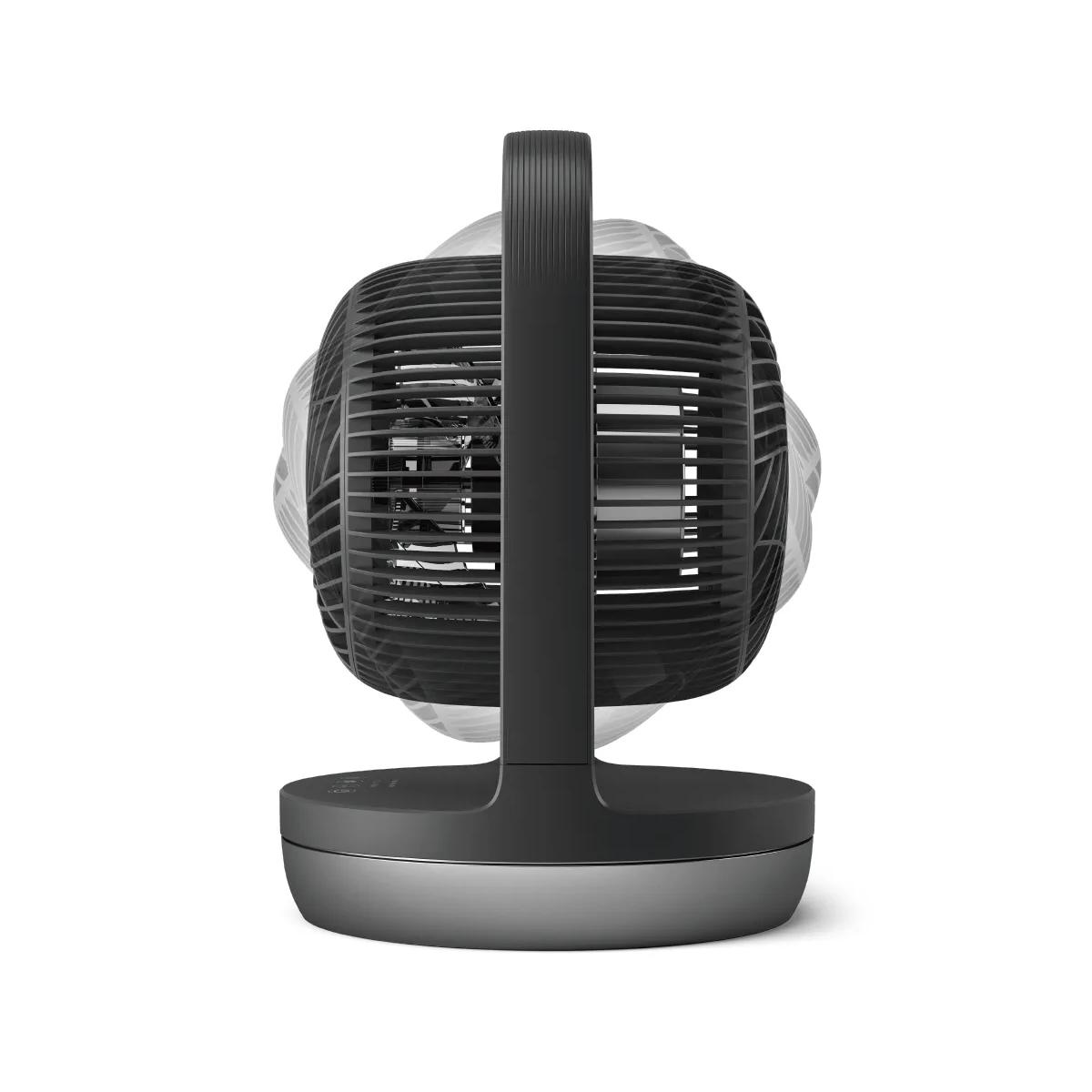 Een zwarte ventilator met handvat op een ronde voet, van achteren gezien.
