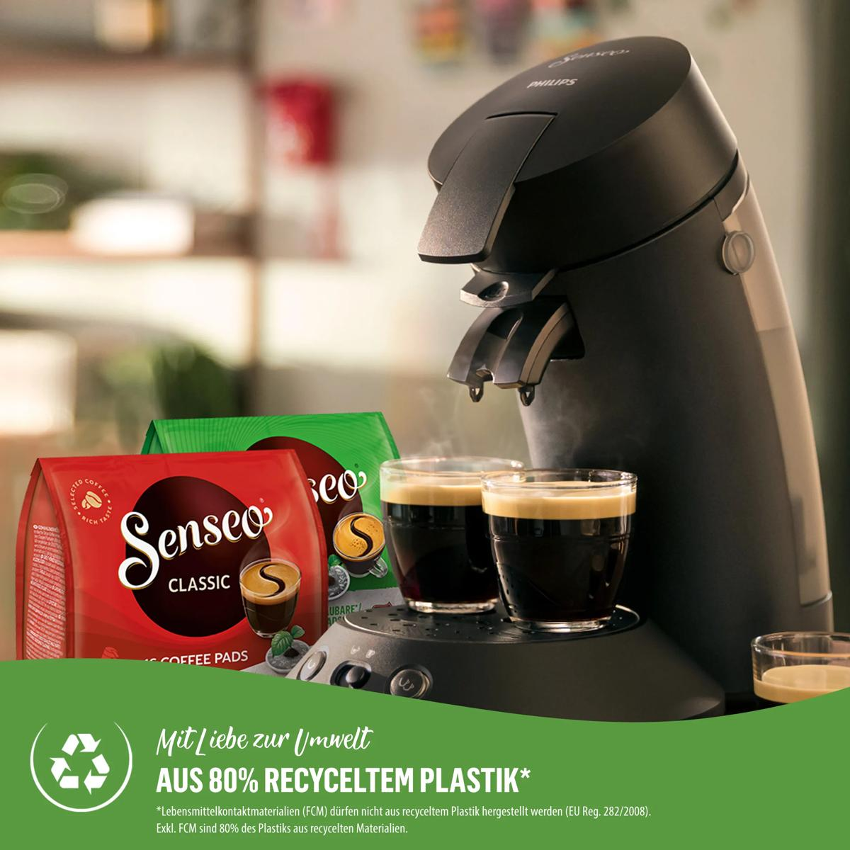 Senseo coffee machine with two glasses of espresso and two packs of coffee pads.