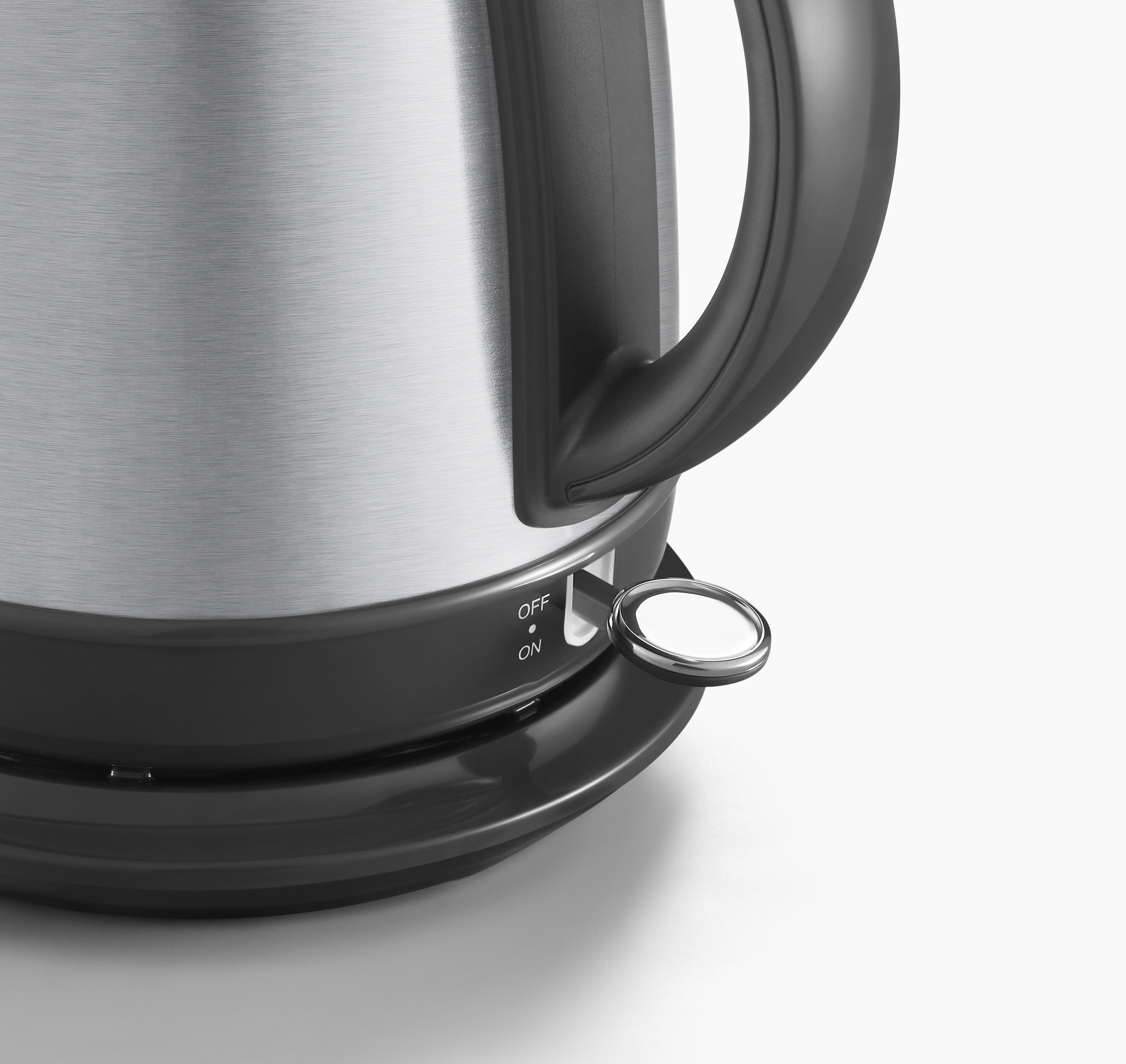 Zbliżenie czajnika z srebrną obudową, czarnym uchwytem i włącznikiem on/off.
