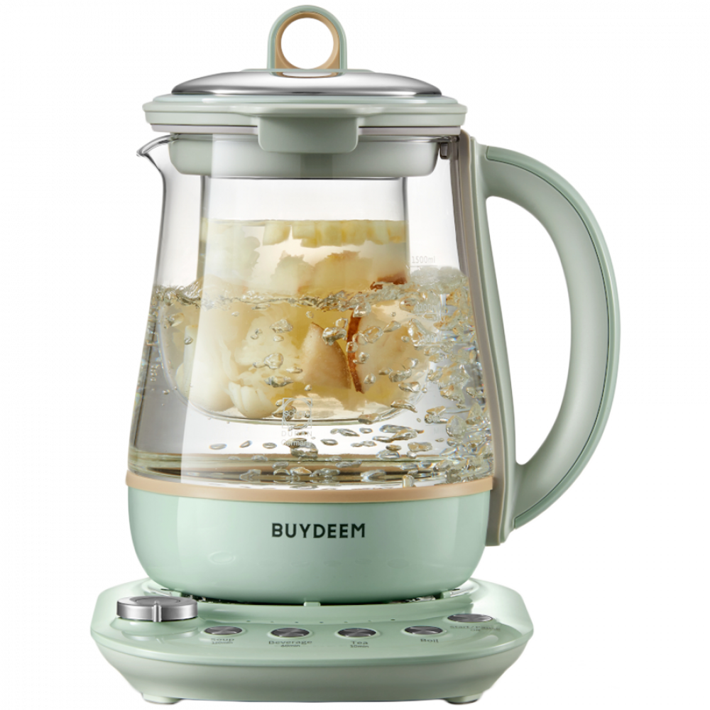 Zielony czajnik gotuje wodę z kawałkami owoców w szklanym naczyniu.