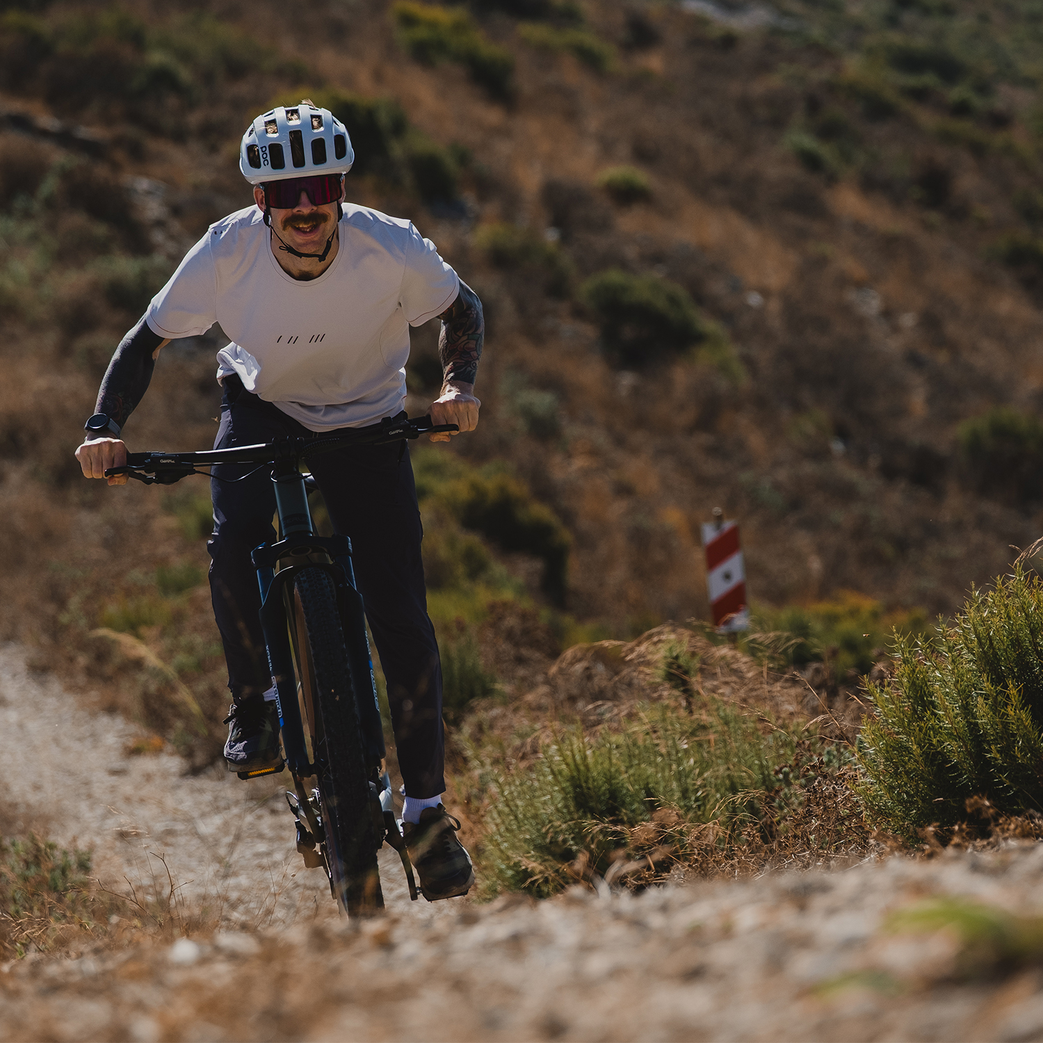 Ein Mann mit Helm fährt Mountainbike auf einem staubigen Pfad im Gebirge.
