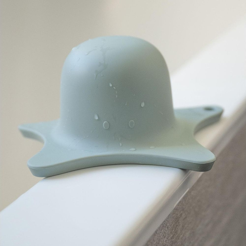 Un polpo giocattolo da bagno in silicone blu chiaro sul bordo della vasca.