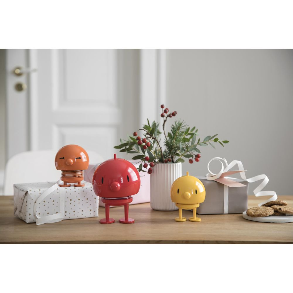 Drei Spielzeugfiguren auf einem Holztisch mit Geschenken und einer Vase.