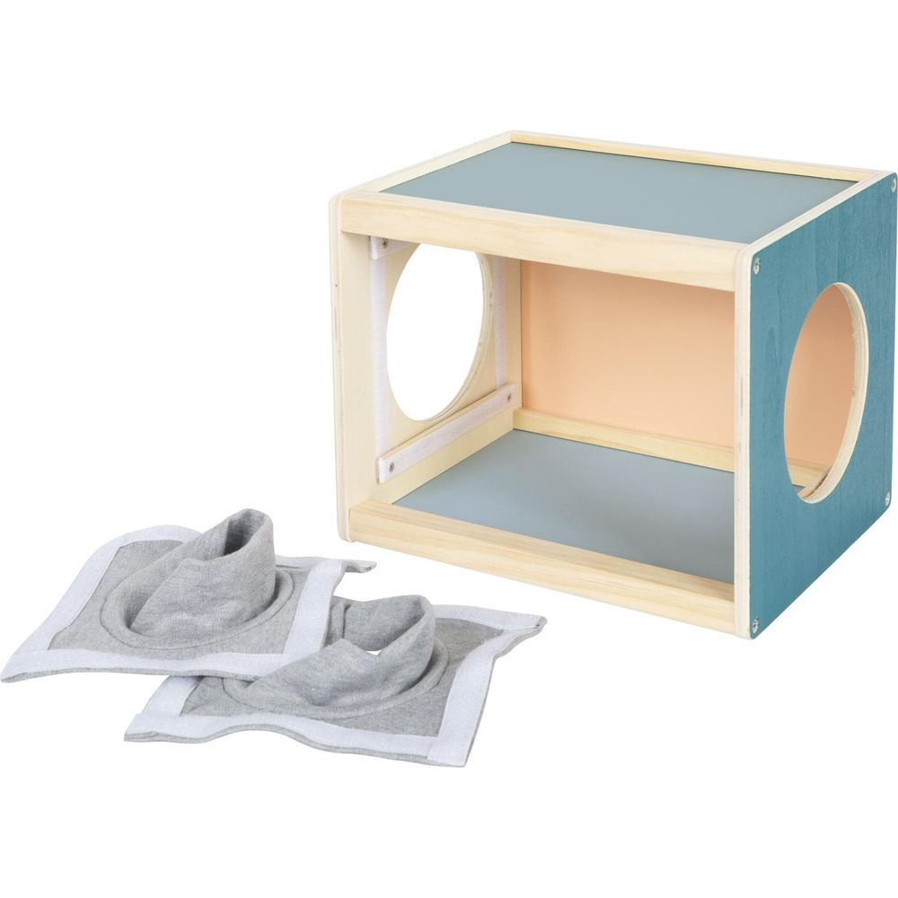 Un cube en bois avec des ouvertures rondes et deux pièces de tissu grises à côté.