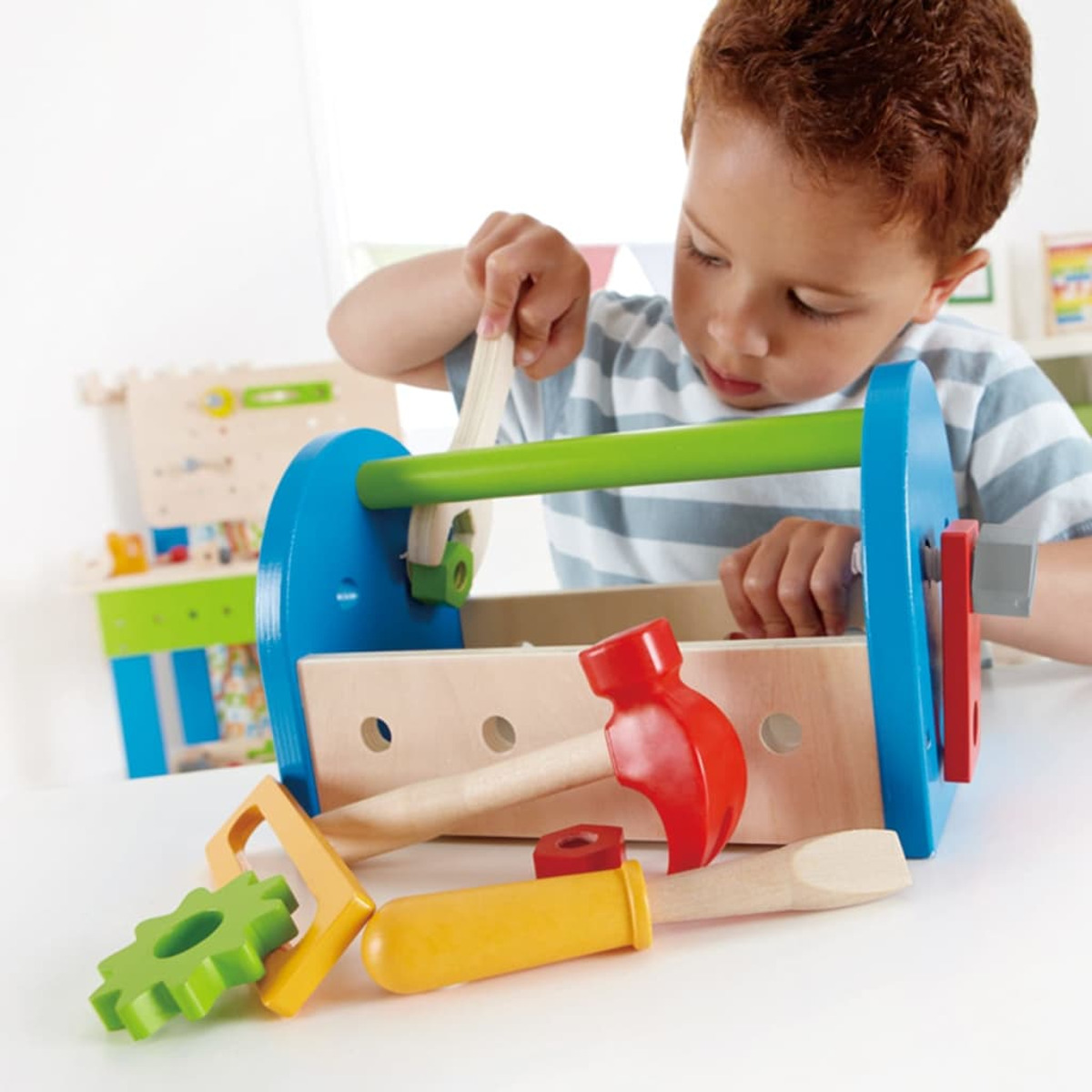 Ein Junge spielt mit einem Holzwerkzeugkasten und Werkzeugen.
