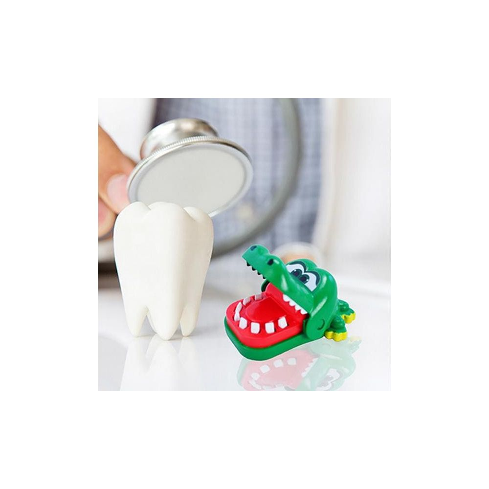 Un giocattolo coccodrillo mordace verde accanto a un modello di dente bianco e stetoscopio.