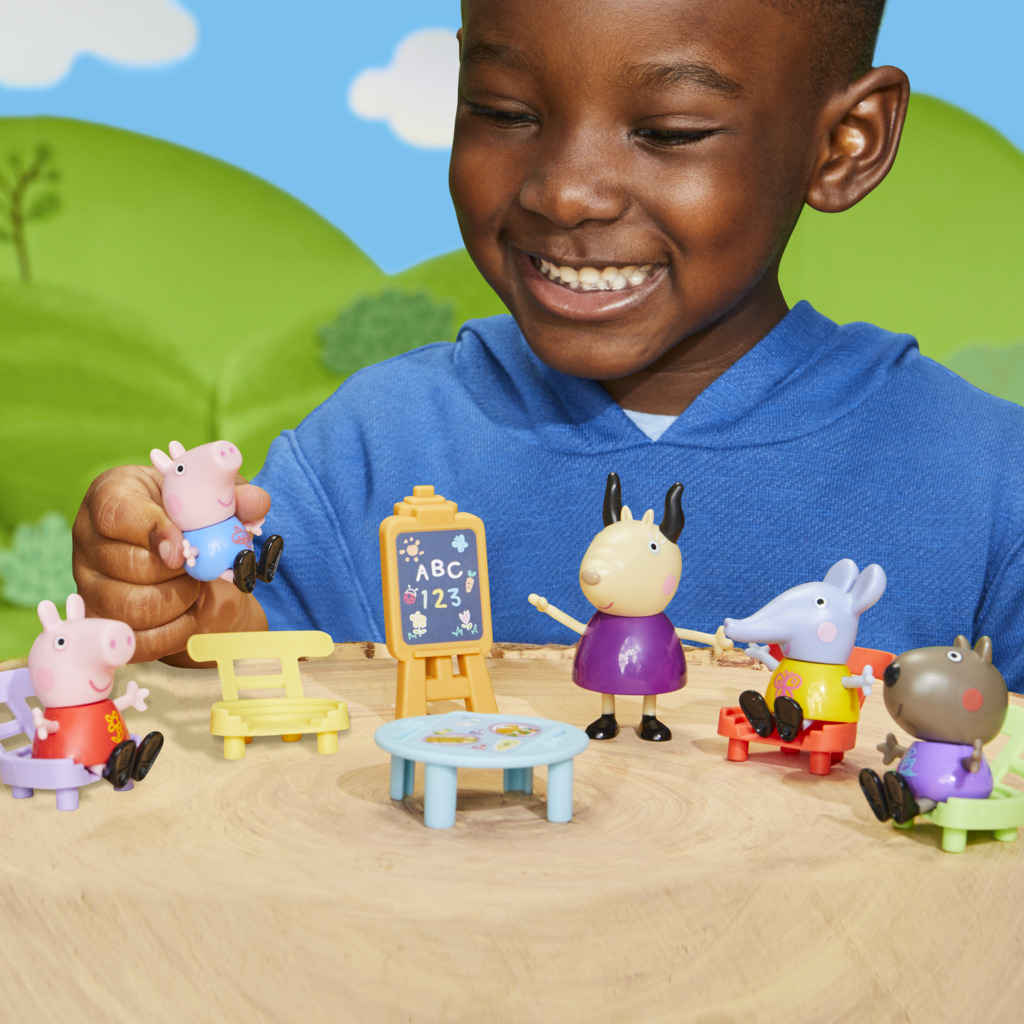 Ein Junge spielt mit Peppa Wutz Figuren: Schweine, eine Ziege, eine Maus und ein Hund.