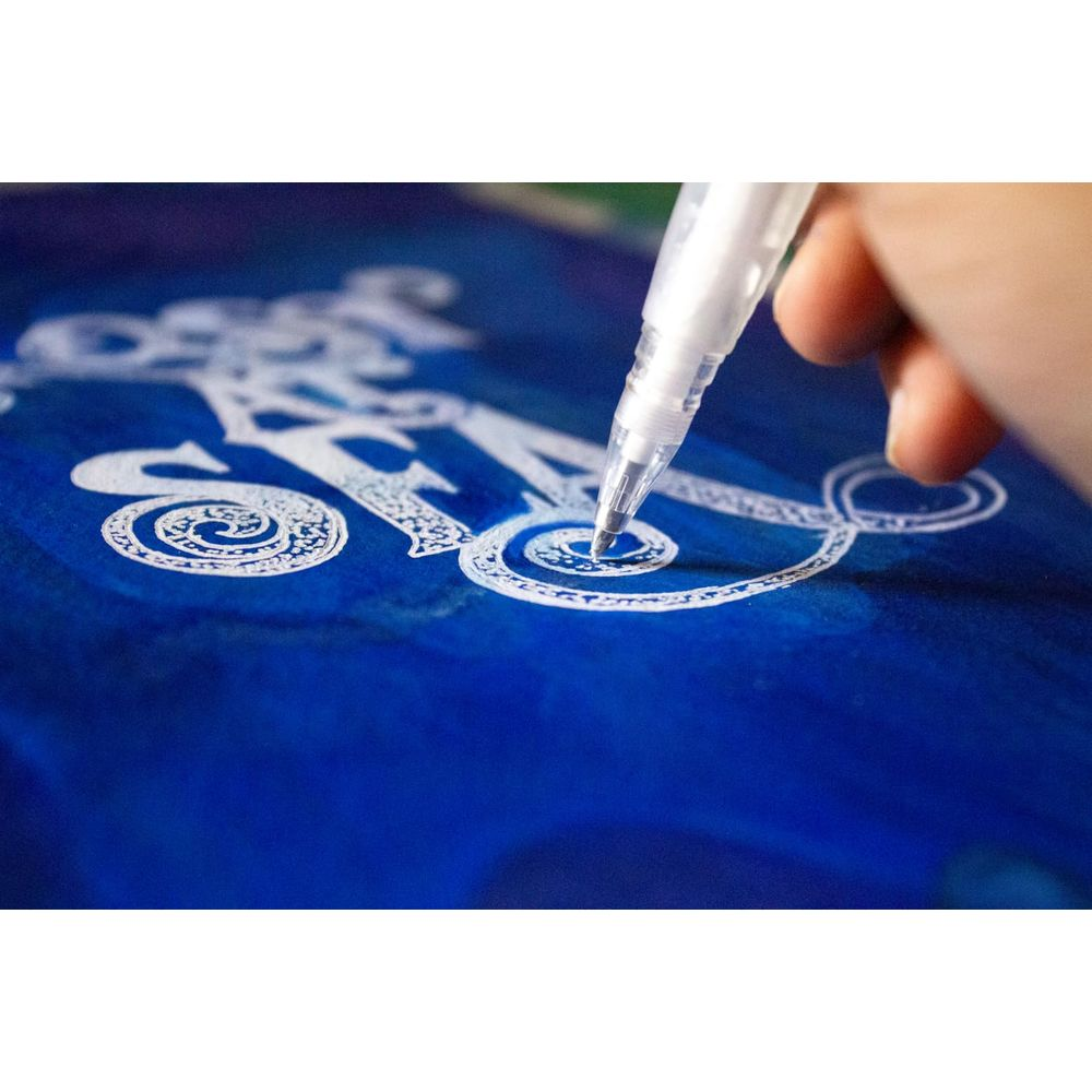 Eine Hand benutzt einen weißen Stift, um auf blauem Papier zu schreiben.
