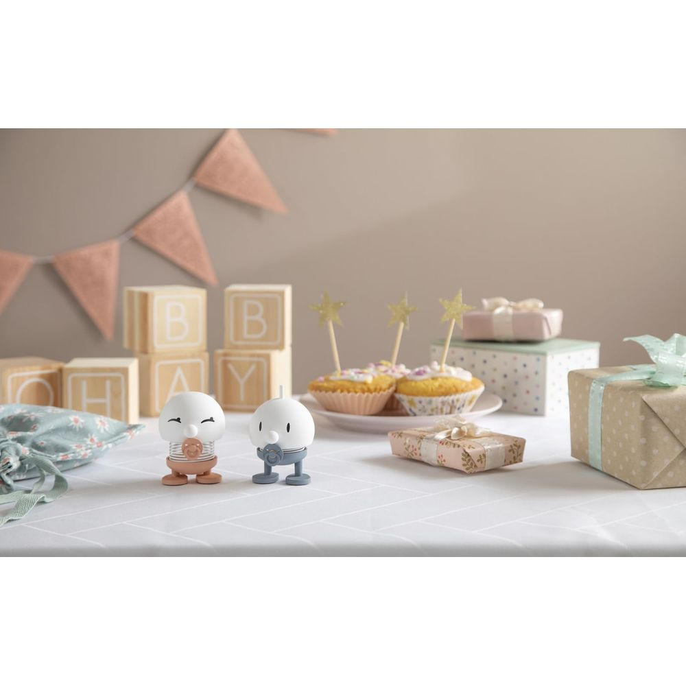 Due figure davanti a blocchi per bambini, muffin e regali su una tovaglia.