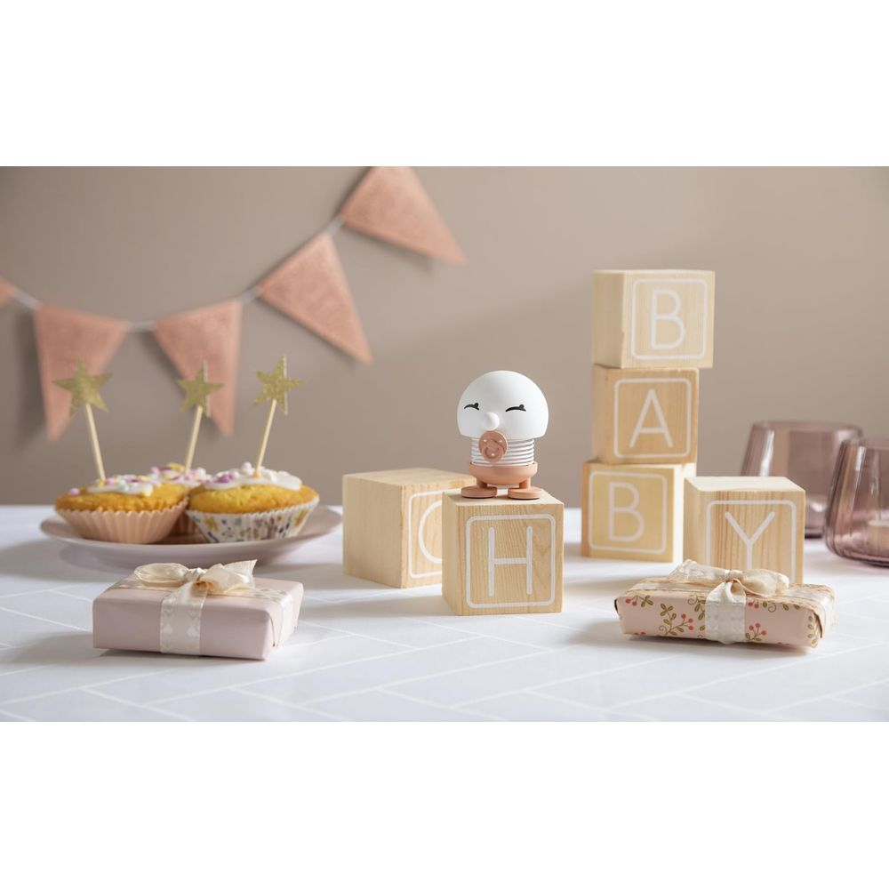Una scena per baby shower con cupcake, regali e blocchi alfabetici che compongono 'BABY'.