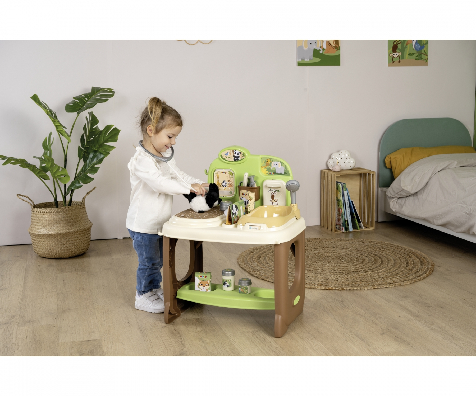 Ein kleines Mädchen spielt mit einem Spielzeug-Tierarzt-Set. Ein Stofftier liegt auf dem Tisch.