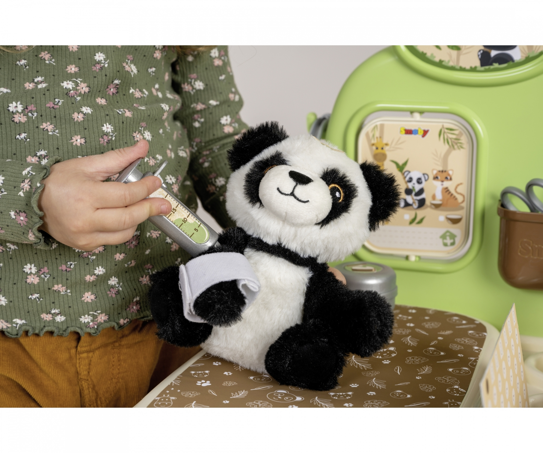 Ein Kind gibt einem Stofftier-Panda eine Spritze. Der Panda hat einen Verband am Arm.