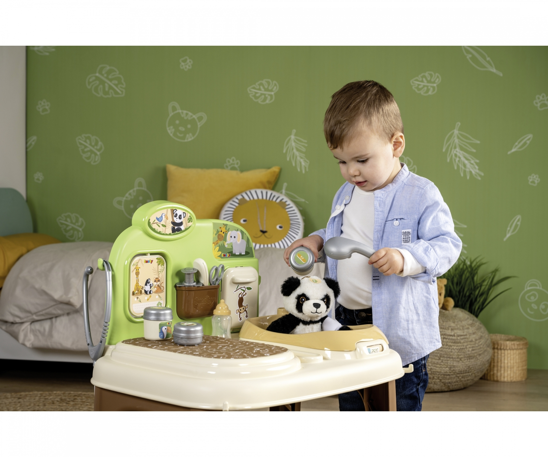 Ein kleiner Junge spielt mit einem Panda-Spielzeug an einem grünen Spielzeug-Waschbecken.