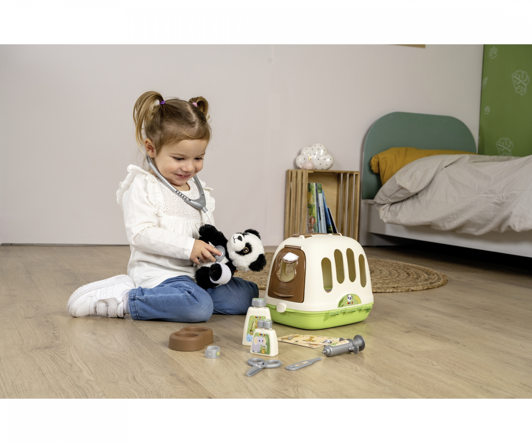 Ein kleines Mädchen spielt mit einem Tierarztkoffer und einem Pandabär.