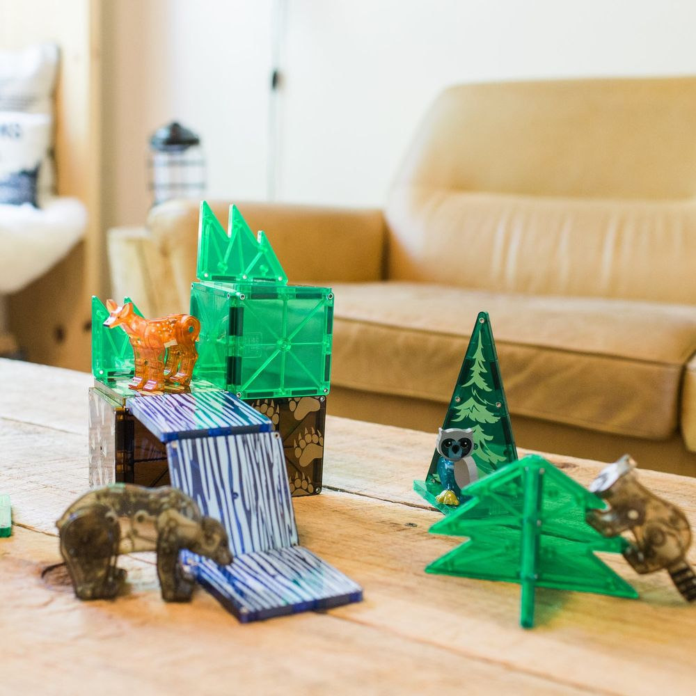 Spielzeugtiere und Bausteine auf einem Holztisch vor einem Sofa.