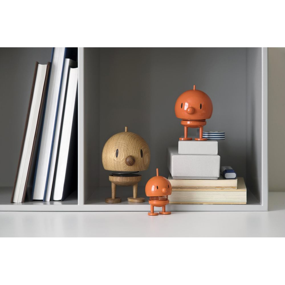 Figure in legno e arancioni su mensola con libri.