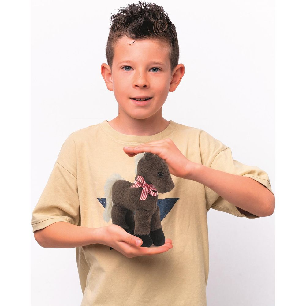 Un ragazzo tiene un piccolo cavallo di peluche marrone con un fiocco rosso.