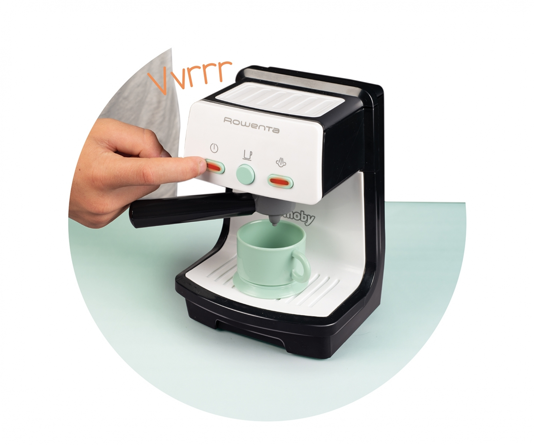 Ein Finger drückt auf den roten Knopf einer Spielzeug-Kaffeemaschine mit einer Tasse.