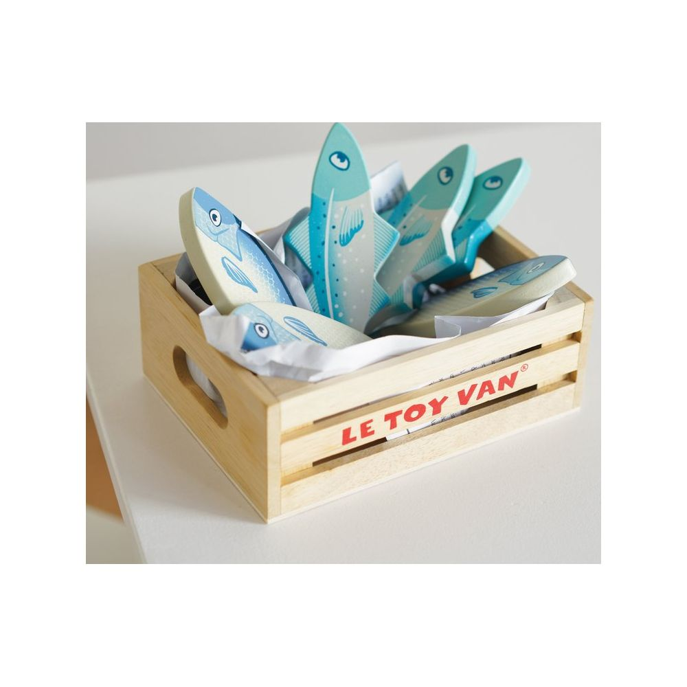 Cassa di legno con sei giocattoli di pesce in legno, dipinti di blu e bianco.