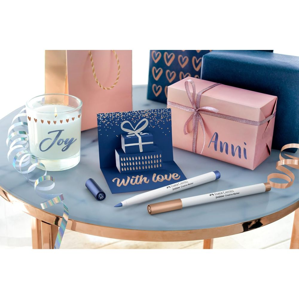 Kerze, Karte, Geschenke und Stifte auf einem Tisch.