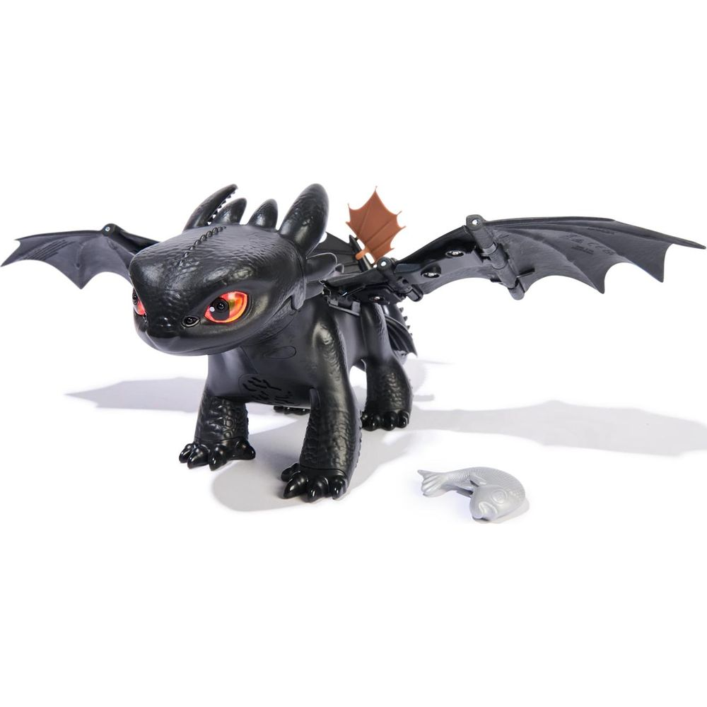 Dragon noir aux yeux rouges et ailes déployées, à côté d'un poisson jouet.