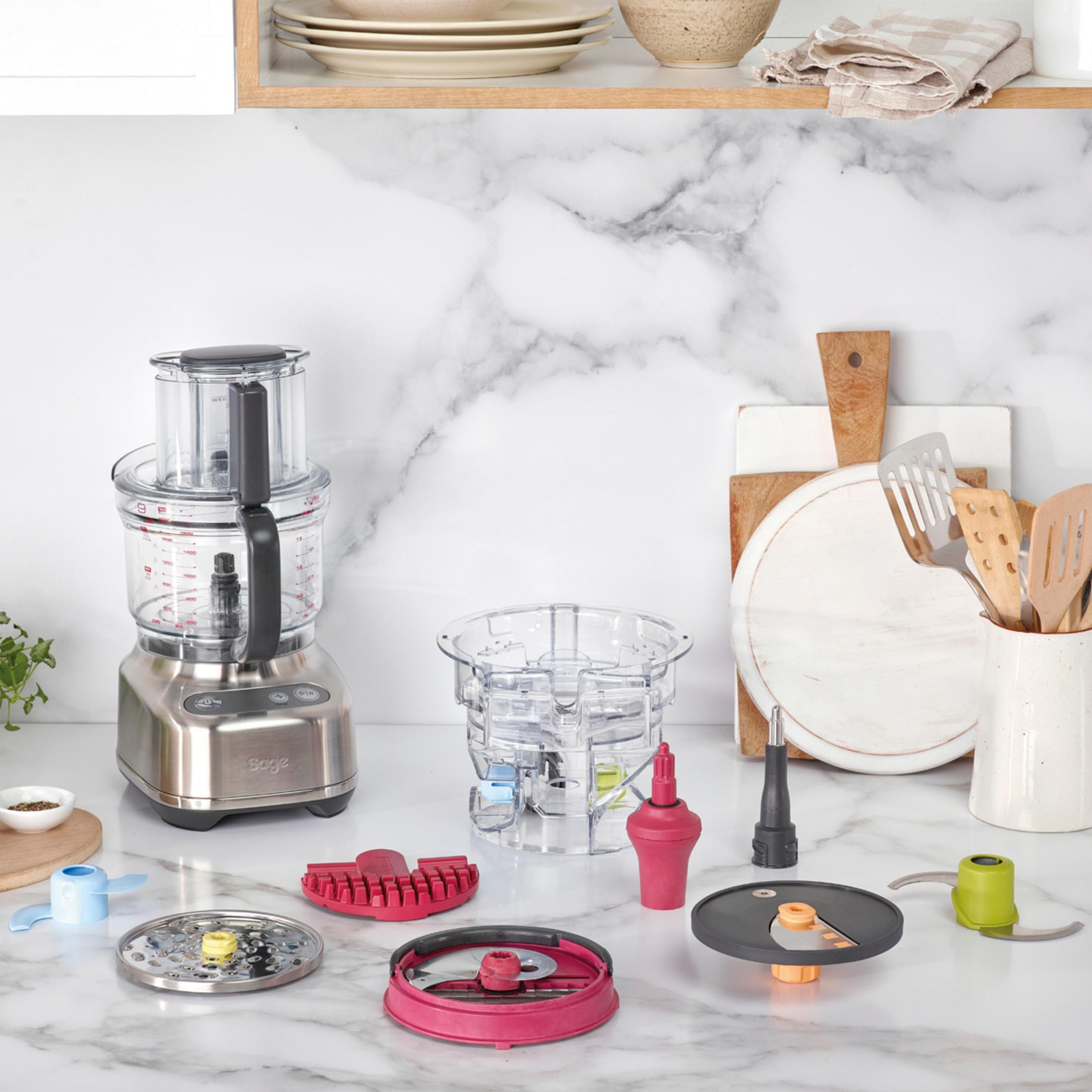 Robot da cucina con accessori su un piano di lavoro in marmo.