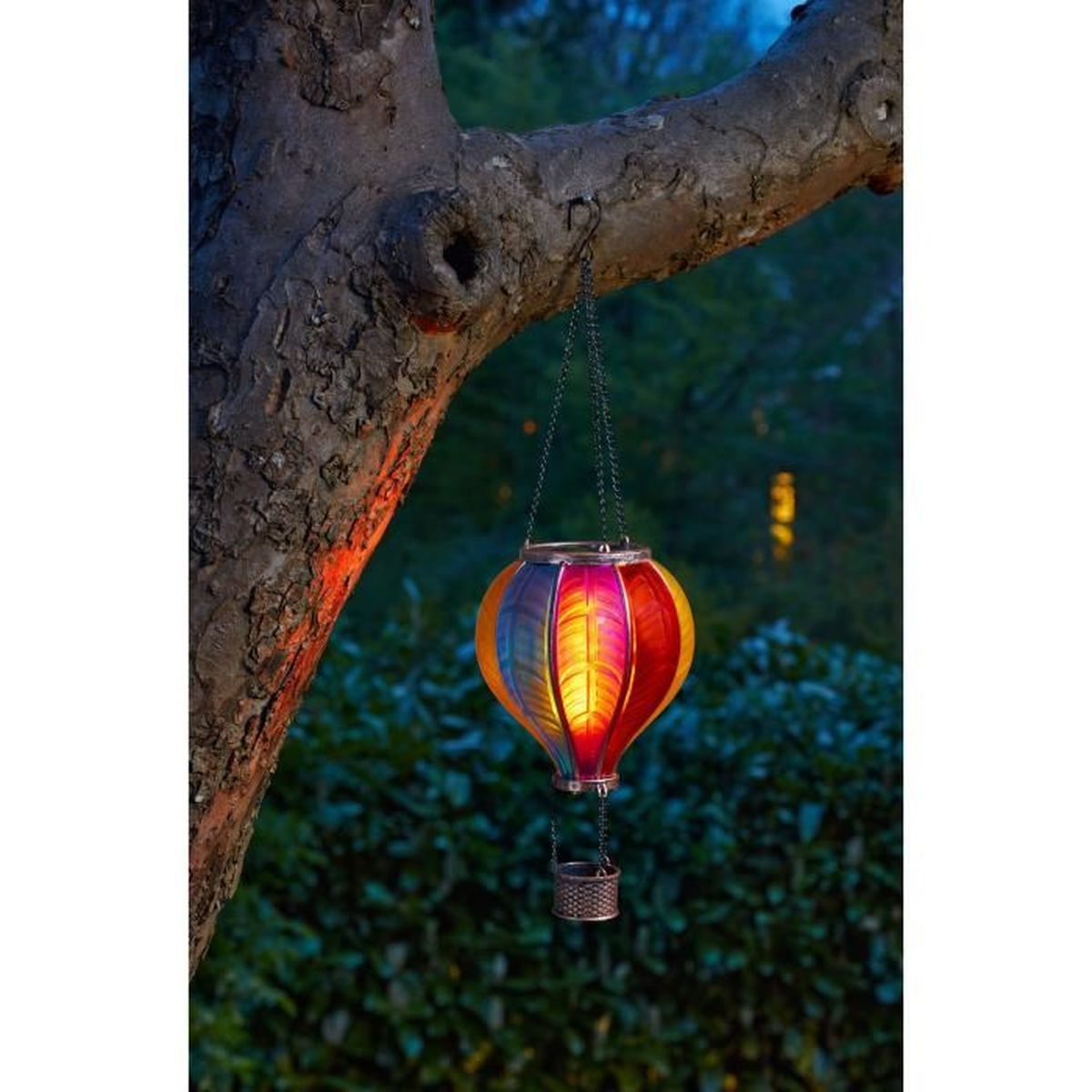 Bunter Heißluftballon-Laterne hängt im Baum im Abendlicht.