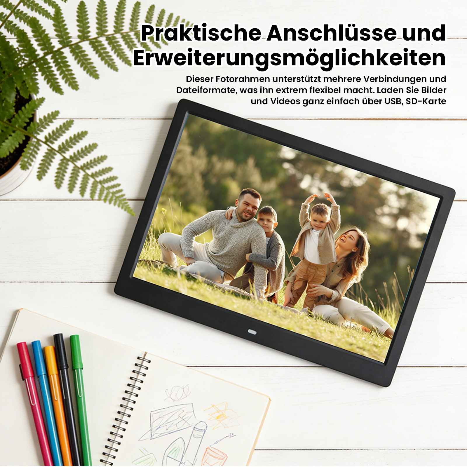 Digitale Bilderrahmen zeigt eine Familie im Freien, daneben ein Notizbuch mit Stiften.