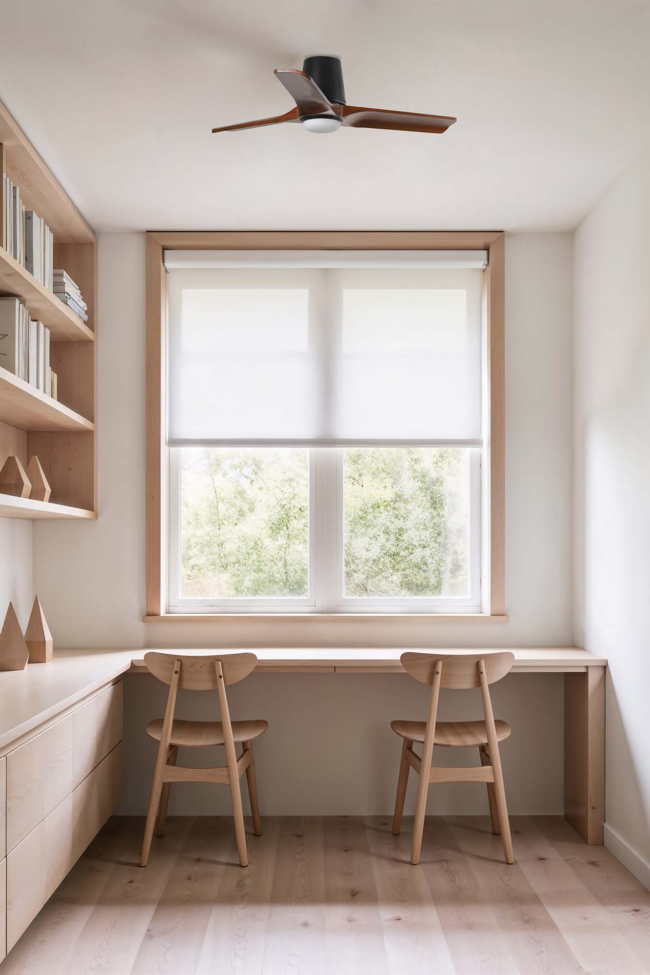 Ein Schlafzimmer mit zwei Schreibtischen, zwei Stühlen und einem Deckenventilator.
