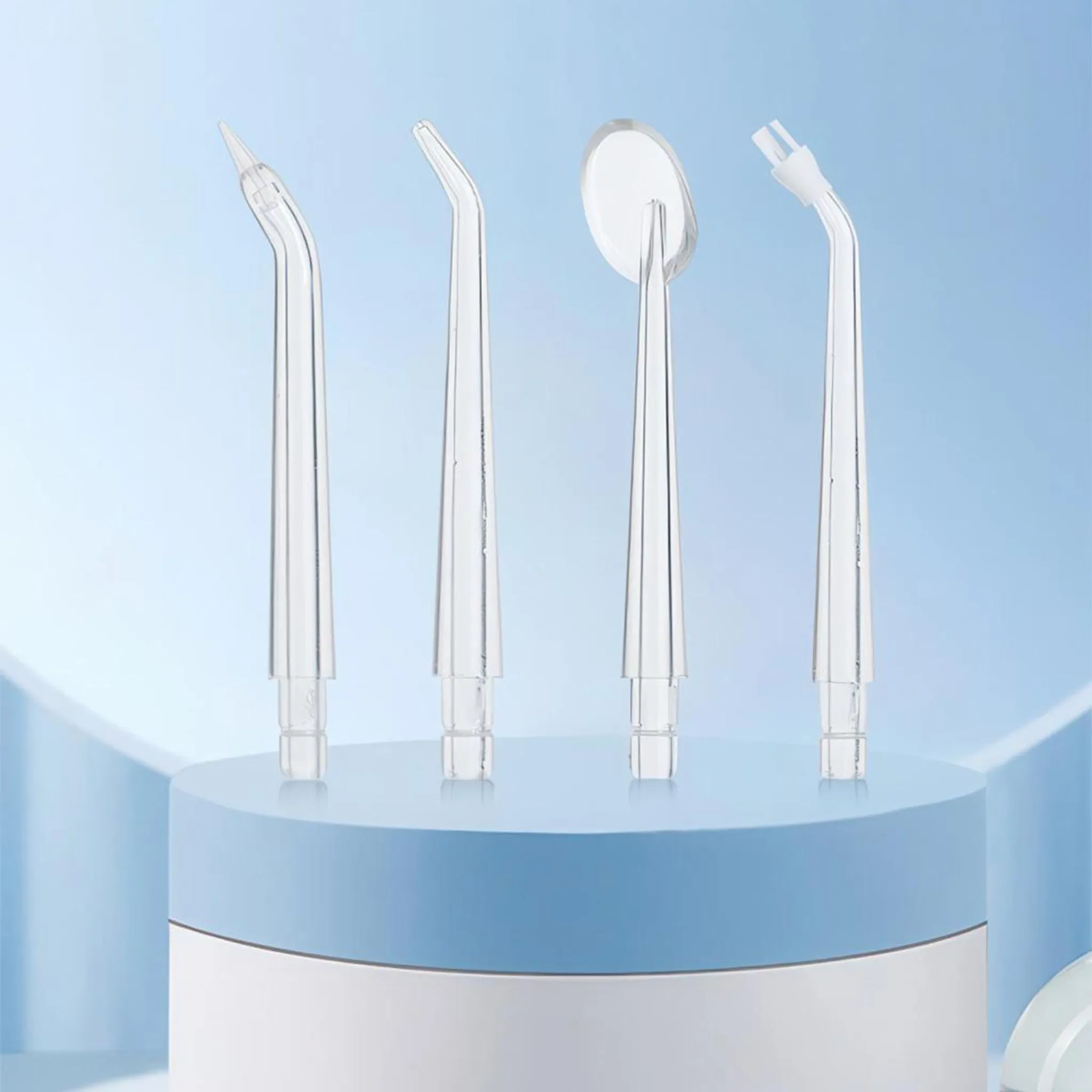 Vier transparente Dentalwerkzeuge auf einem Sockel vor blauem Hintergrund.