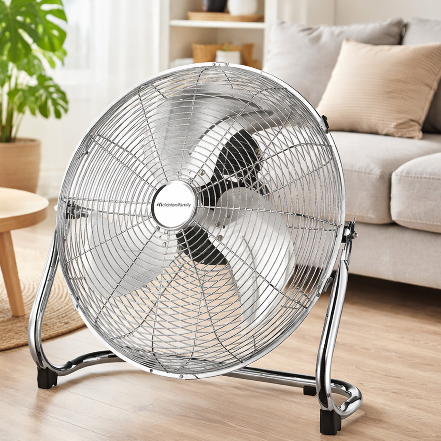 Un ventilador de suelo plateado se encuentra en una sala de estar junto a un sofá y una mesa.