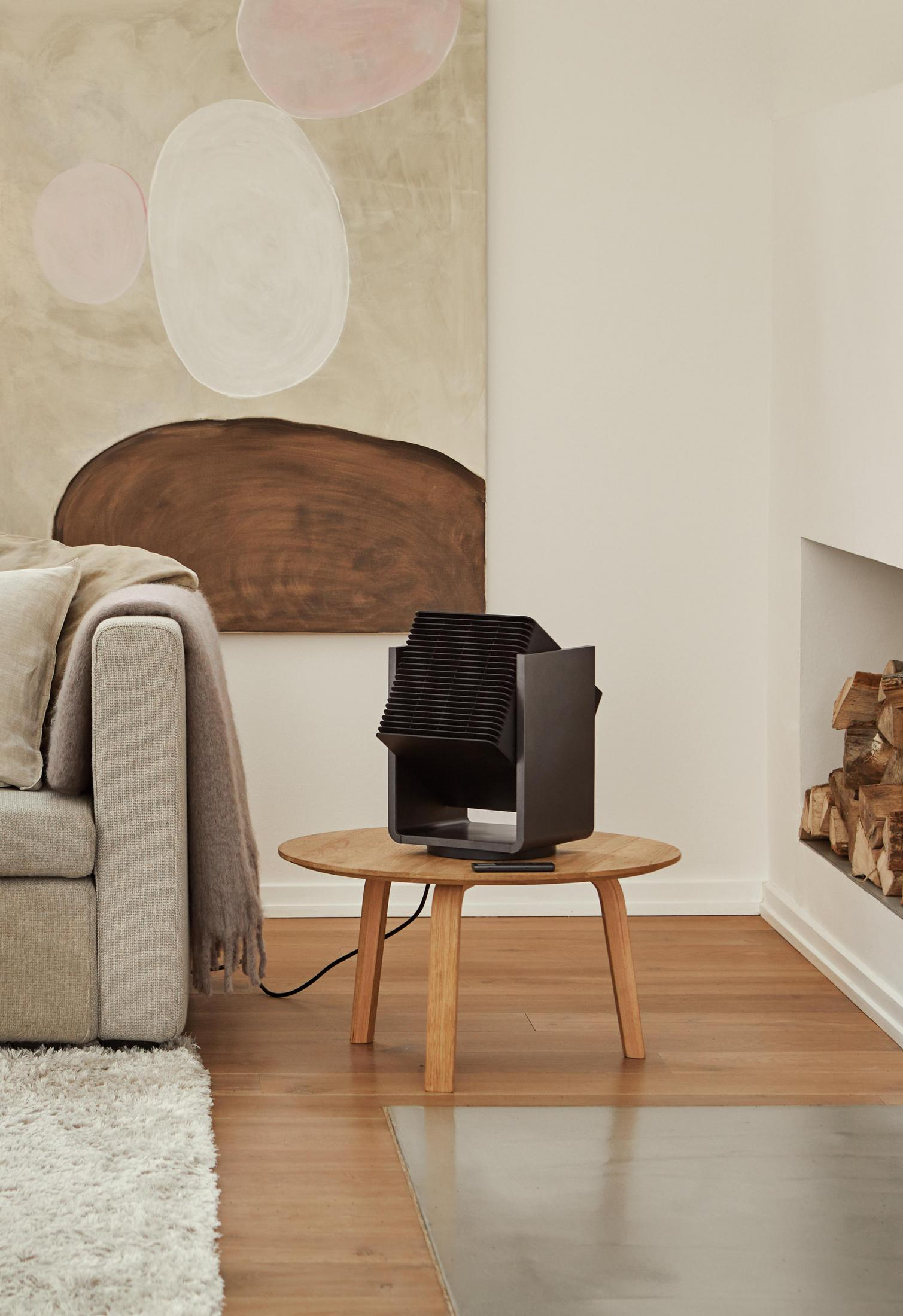 Una zona soggiorno moderna con divano, tavolo in legno e ventilatore nero.