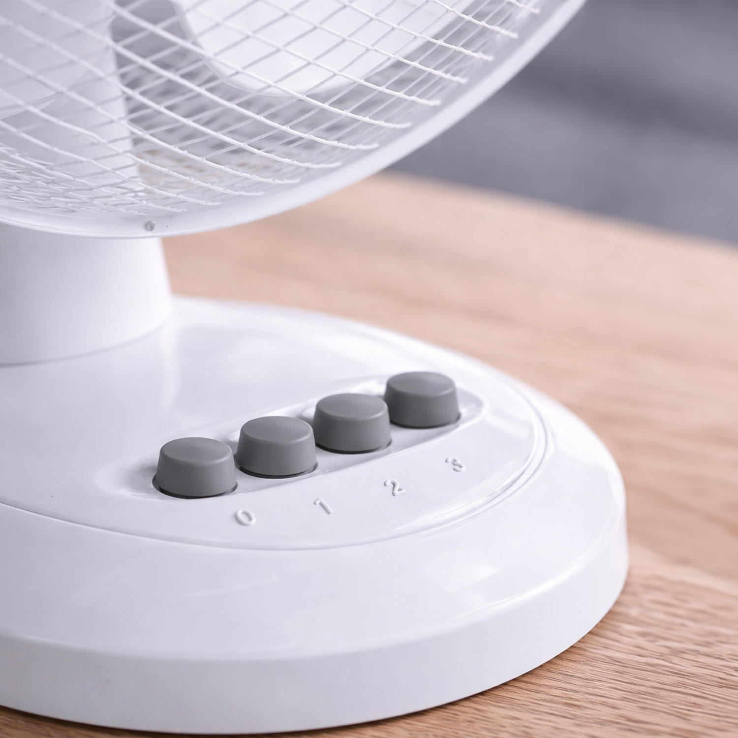 Primer plano de un ventilador blanco con botones grises e indicadores de velocidad 0, 1, 2, 3.