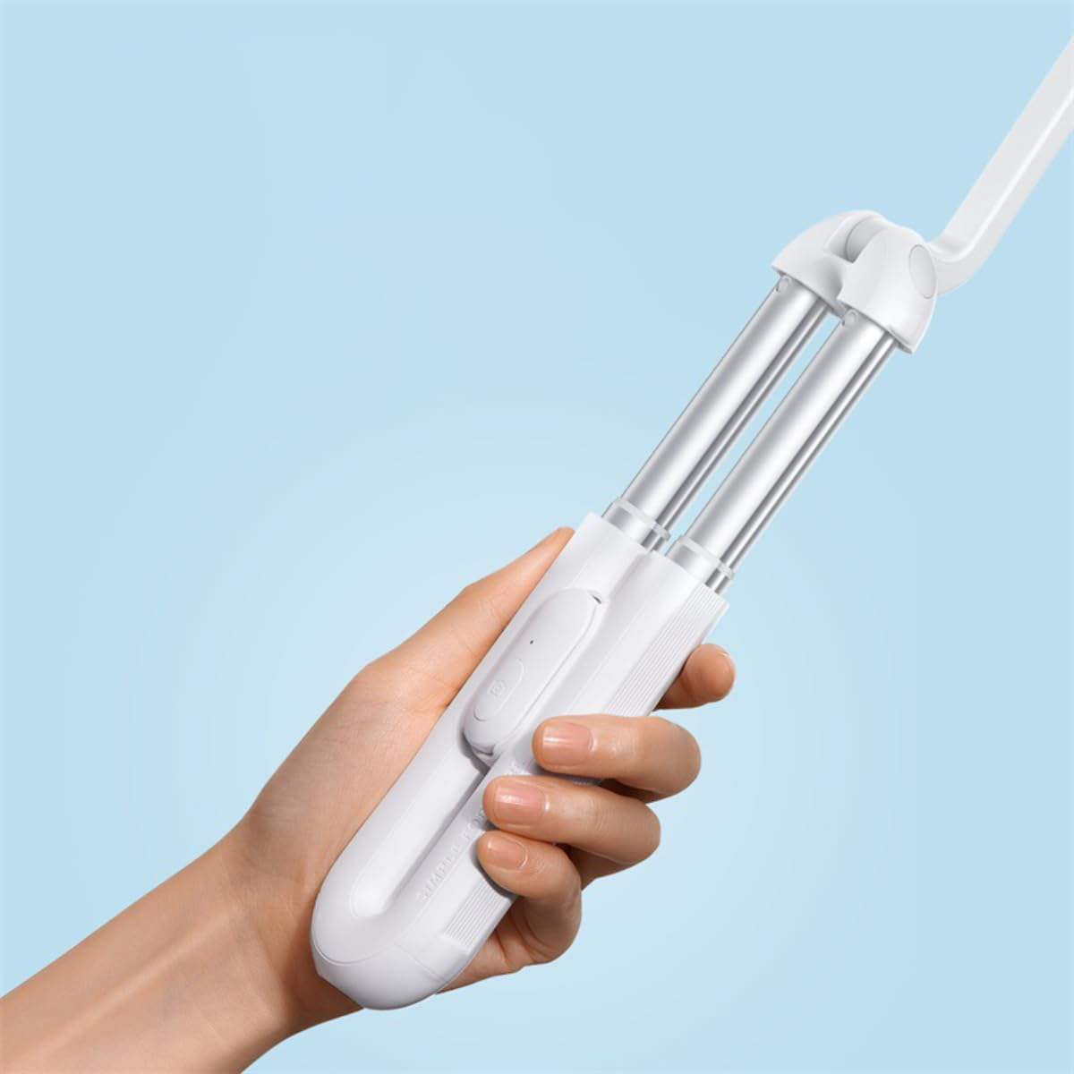 Una mano tiene un selfie stick bianco estensibile su sfondo blu.