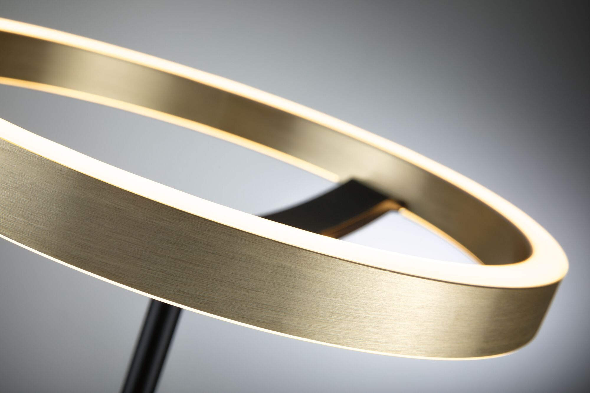 Ein goldener Ring mit integrierter Beleuchtung auf einem schwarzen Ständer.