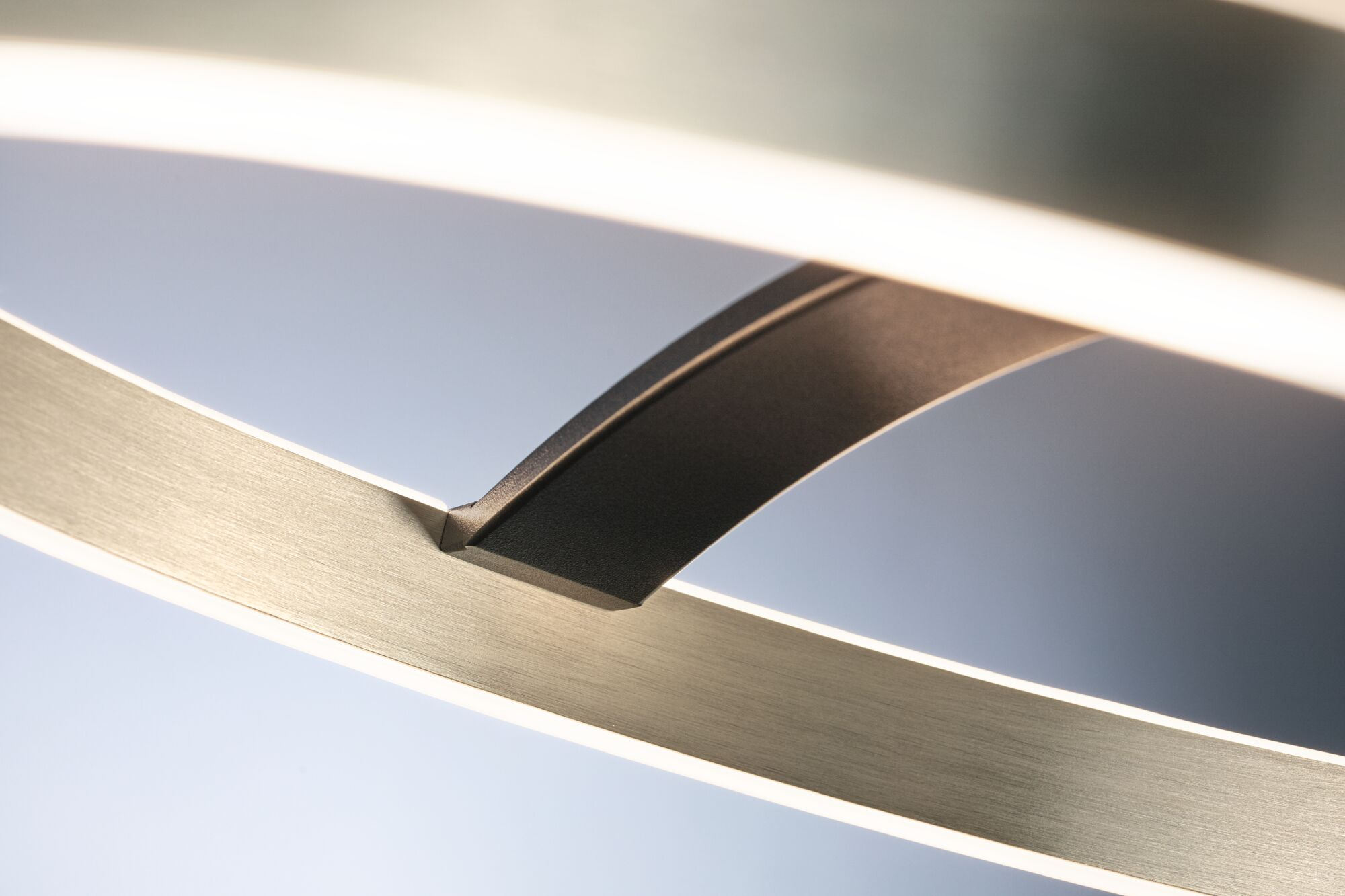 Nahaufnahme einer modernen Leuchte mit gebürstetem Metall und Lichtstreifen.