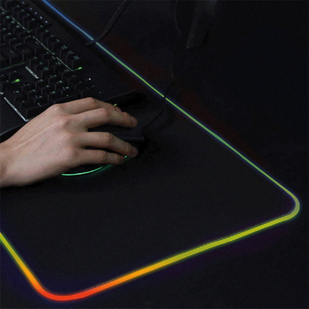 Una mano aziona un mouse su un tappetino per mouse da gioco illuminato con tastiera.