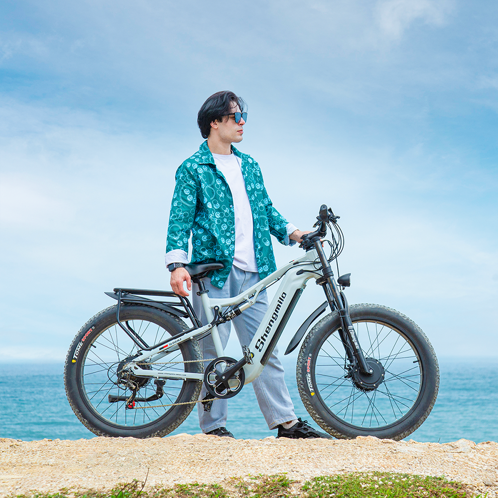 Mann mit Fahrrad am Meer, blauer Himmel, Sandstrand.