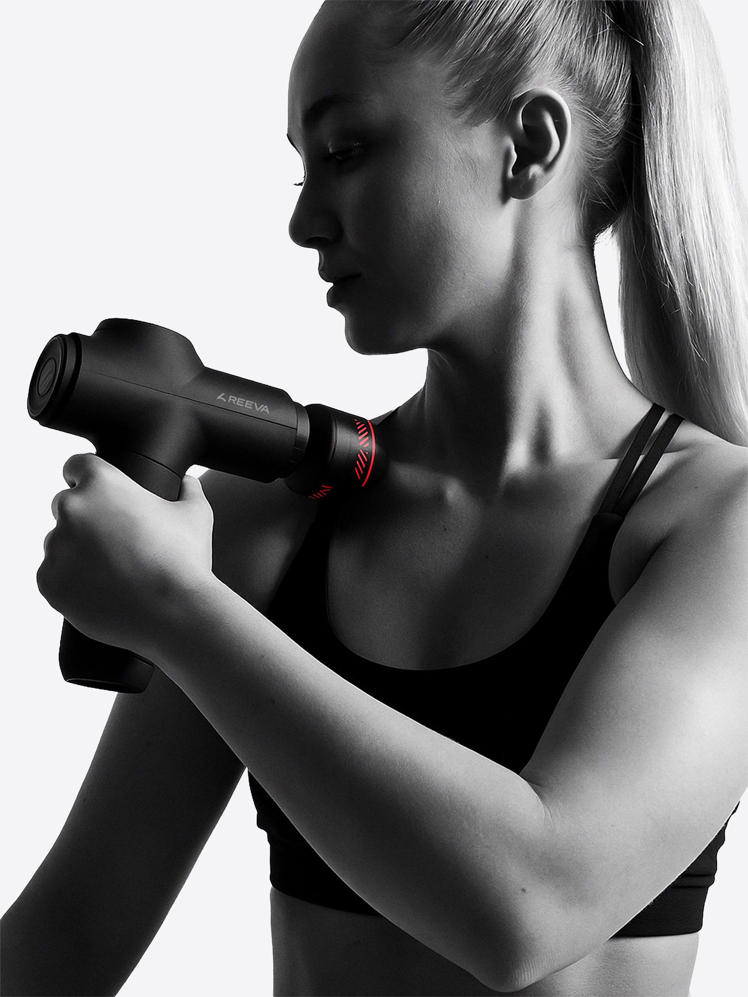 Frau mit Massagepistole am Nacken, schwarze Sportkleidung, helle Hintergrund