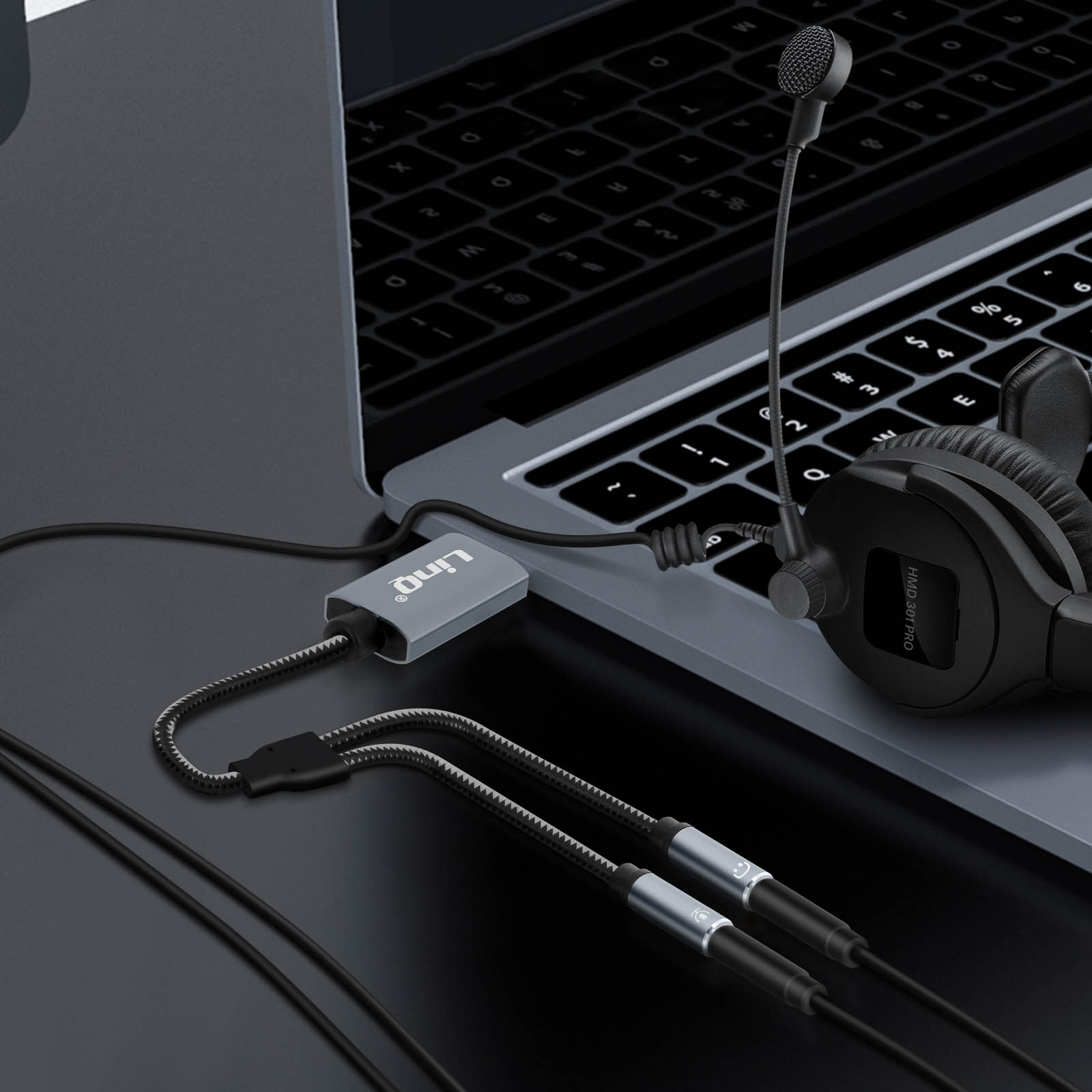 Un adattatore grigio collega un auricolare con microfono a un laptop.