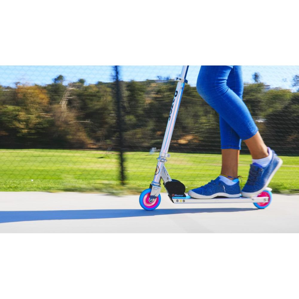 Persona cavalca monopattino in jeans blu e scarpe da ginnastica all'aperto