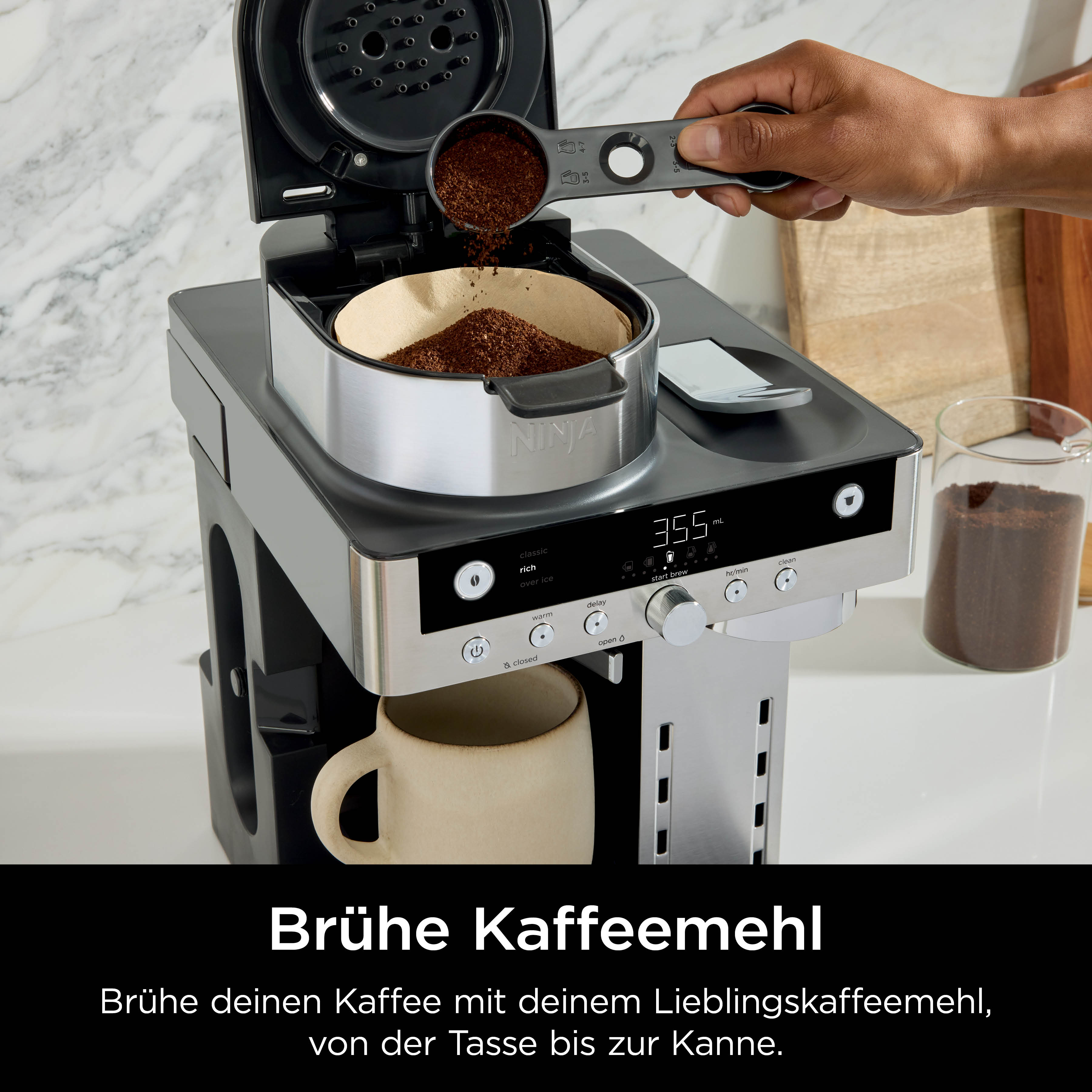Una mano versa caffè macinato da un misurino in una macchina da caffè.