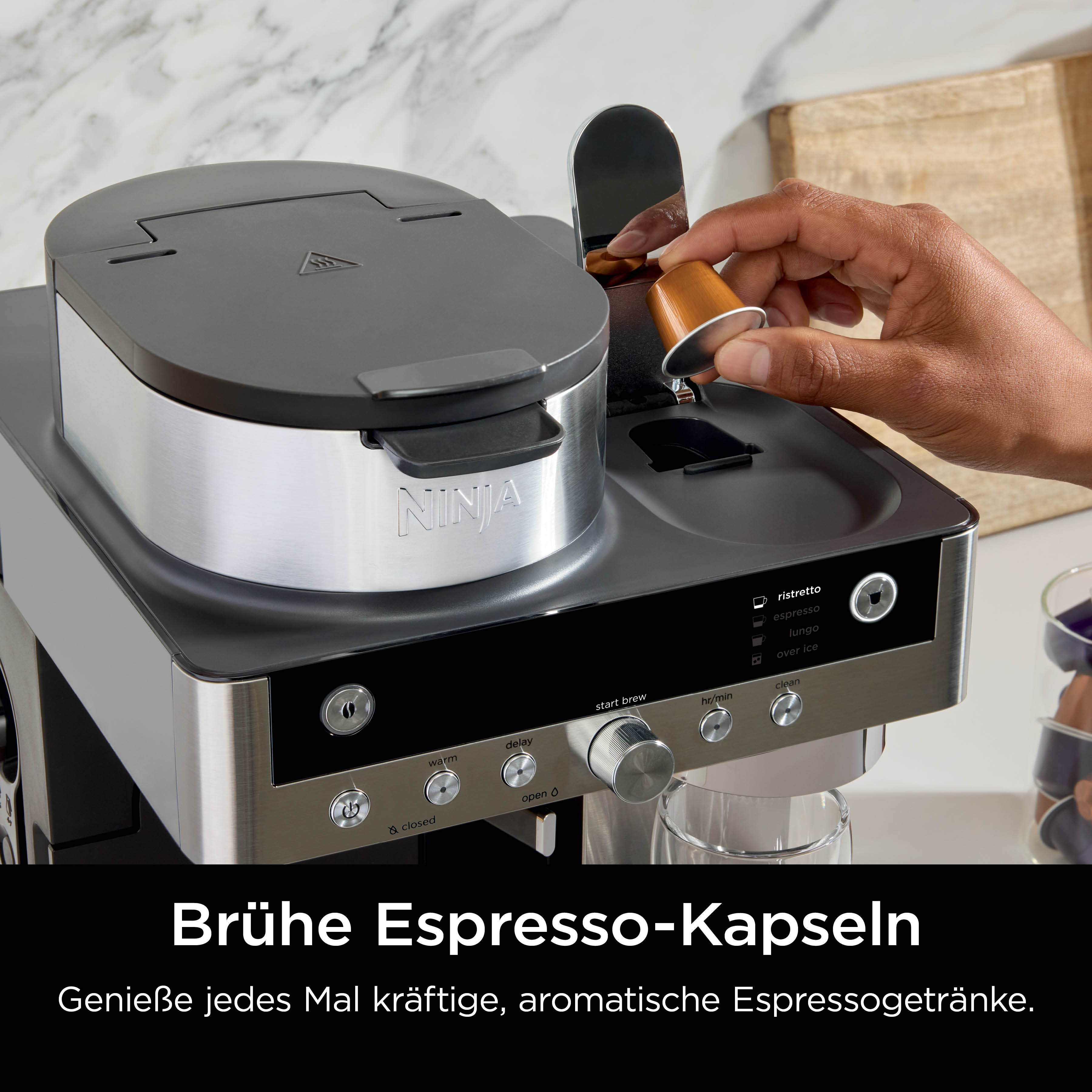 Una mano inserisce una capsula di caffè in una macchina da caffè Ninja.